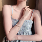 Pearl bracelet on wrist with gold clasp and green and white bead charms