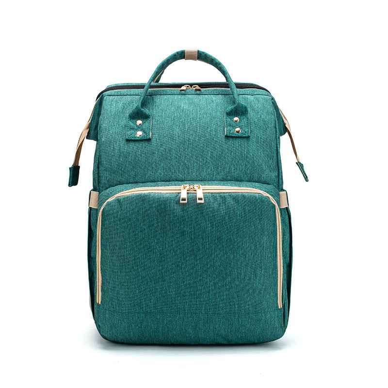 Teal green foldable baby travel bed backpack with beige trim, top handle, and front pocket