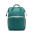 Teal green foldable baby travel bed backpack with beige trim, top handle, and front pocket