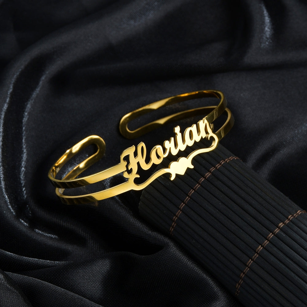 Gold personalized cuff bracelet with engraved cursive name, worn on wrist