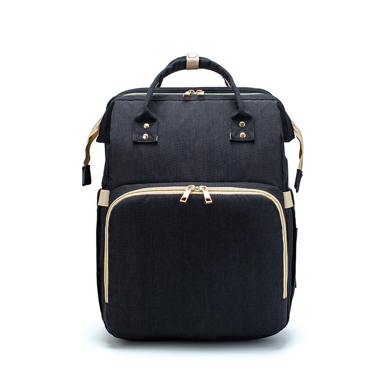 Black foldable baby travel bed backpack with beige trim and top handle straps