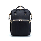 Black foldable baby travel bed backpack with beige trim and top handle straps