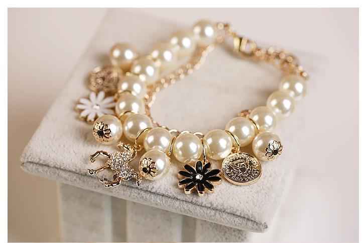 Gold-tone pearl charm bracelet with coin medallions, flower charms, and horse dangle