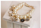 Gold-tone pearl charm bracelet with coin medallions, flower charms, and horse dangle
