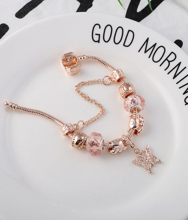 Rose gold bracelet with pink bead charms and a small cross dangle on the chain.
