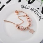 Rose gold bracelet with pink bead charms and a small cross dangle on the chain.