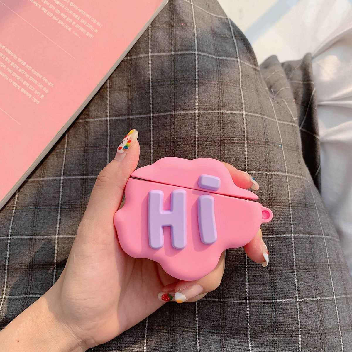 Pink silicone cloud AirPods case with “Hi” letters, showing charging earbuds inside