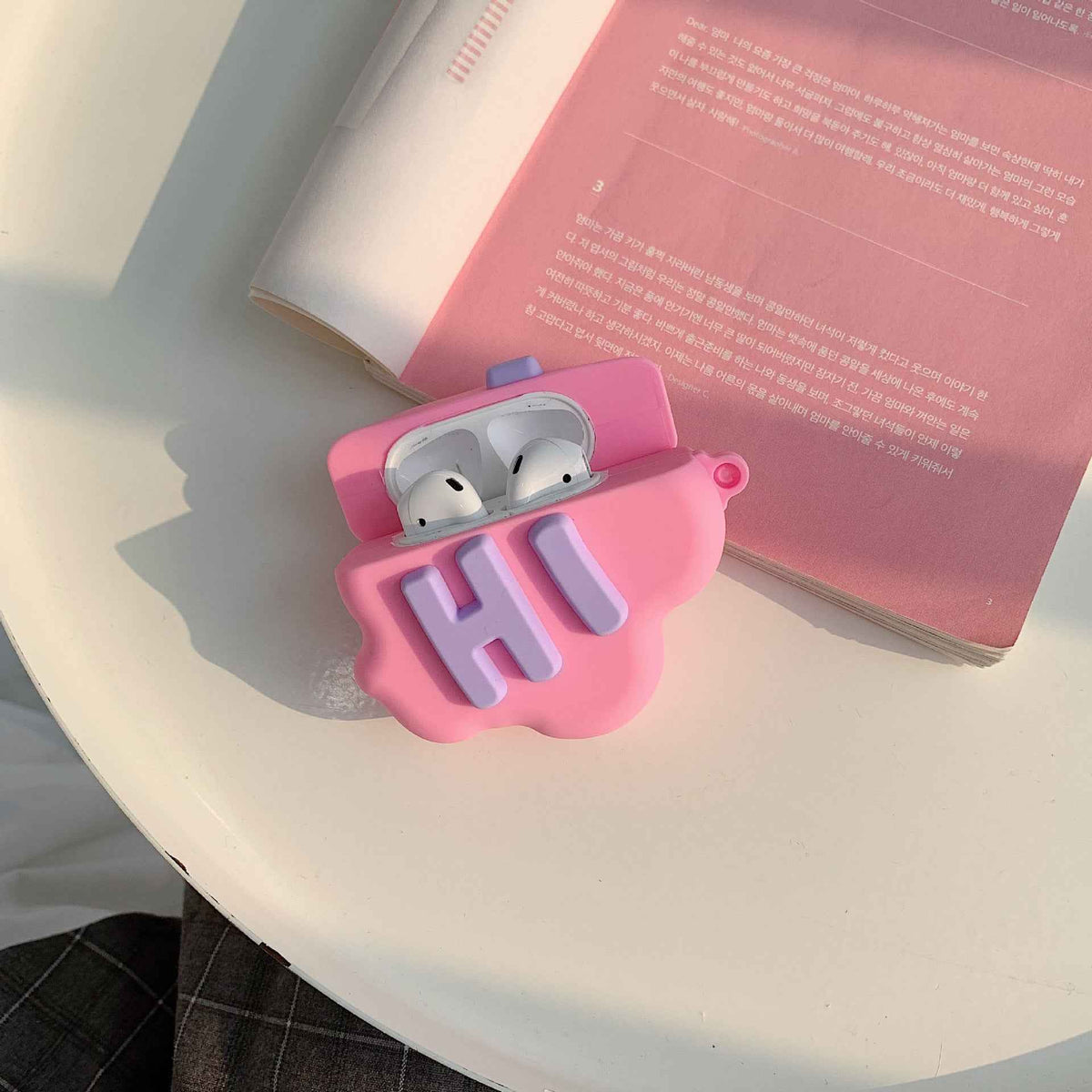Pink silicone cloud AirPods case with “Hi” letters, earbuds visible through the open front