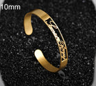 Gold stainless steel cuff bracelet with engraved cursive name and open-heart detail