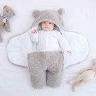 Grey quilted baby sleeping bag with hood, bear ears, and fuzzy footed pants
