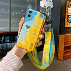 Blue and yellow iPhone case with heart print, gold-toned hardware, and wrist lanyard