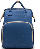 Blue foldable baby travel bed backpack with beige trim, front pocket, and top handle
