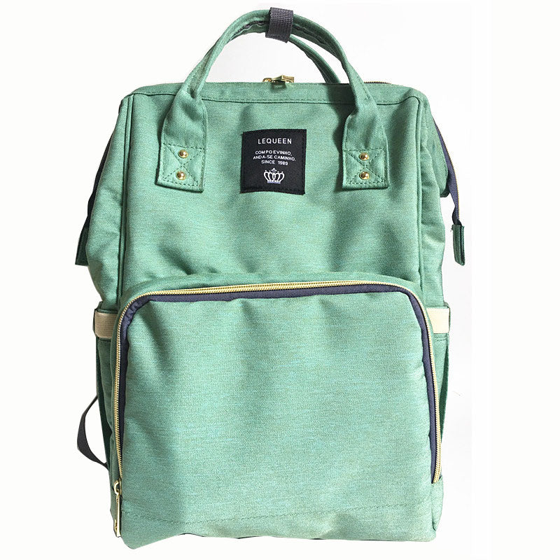 Maternity diaper bag in green with front zipper pocket and black-trim interior panel