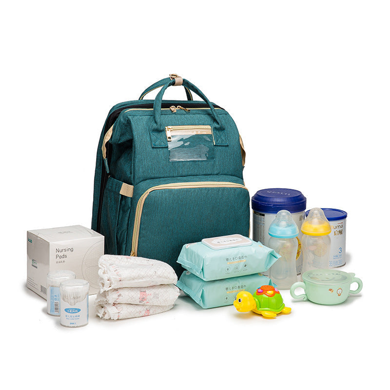 Teal foldable baby travel bed backpack with baby items, bottles, and accessories shown.