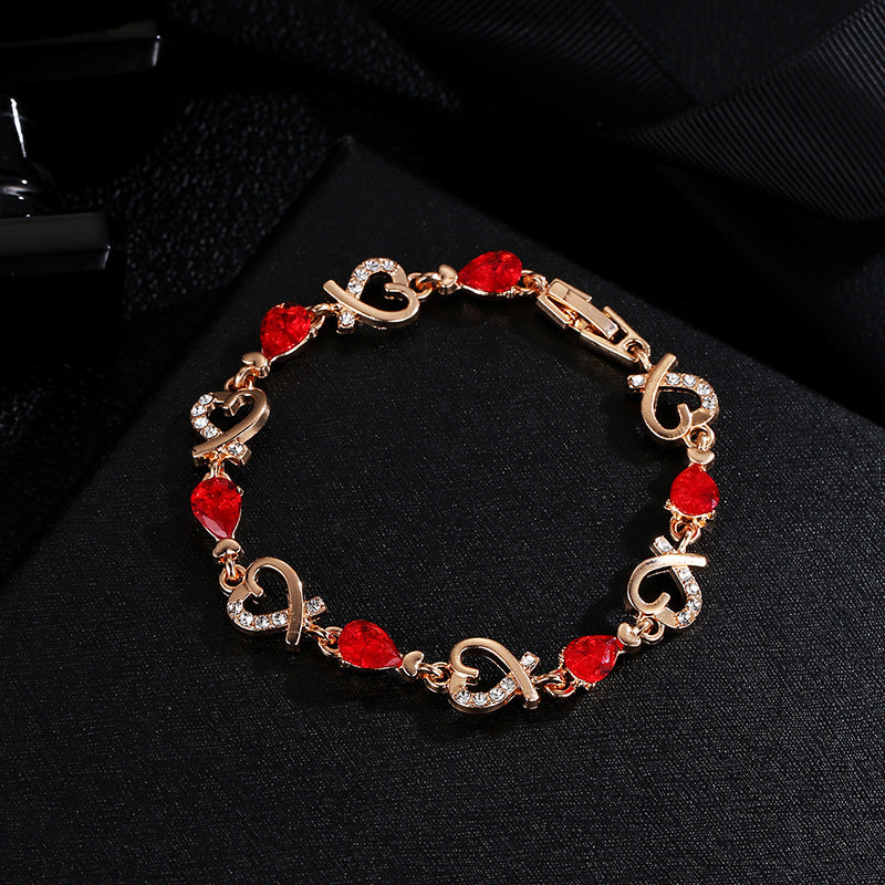 Gold-tone charm bracelet with red heart rhinestone links and heart-shaped clasp