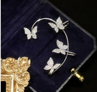 Silver butterfly earrings on a hoop-style frame, with clip backing in a jewelry box