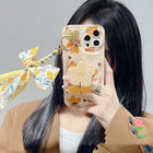 Floral bow phone case with bear-and-flower print, ring holder, and ribbon bow detail
