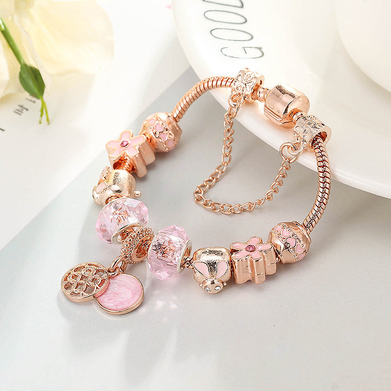 Rose gold bracelet with pink crystal beads, turtle-like charm, and heart coin pendant.