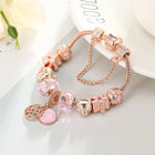 Rose gold bracelet with pink crystal beads, turtle-like charm, and heart coin pendant.