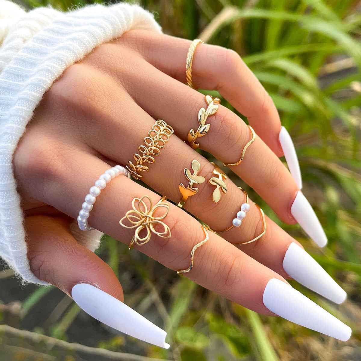 Gold-tone openwork flower rings on hand with pearl and gold bands