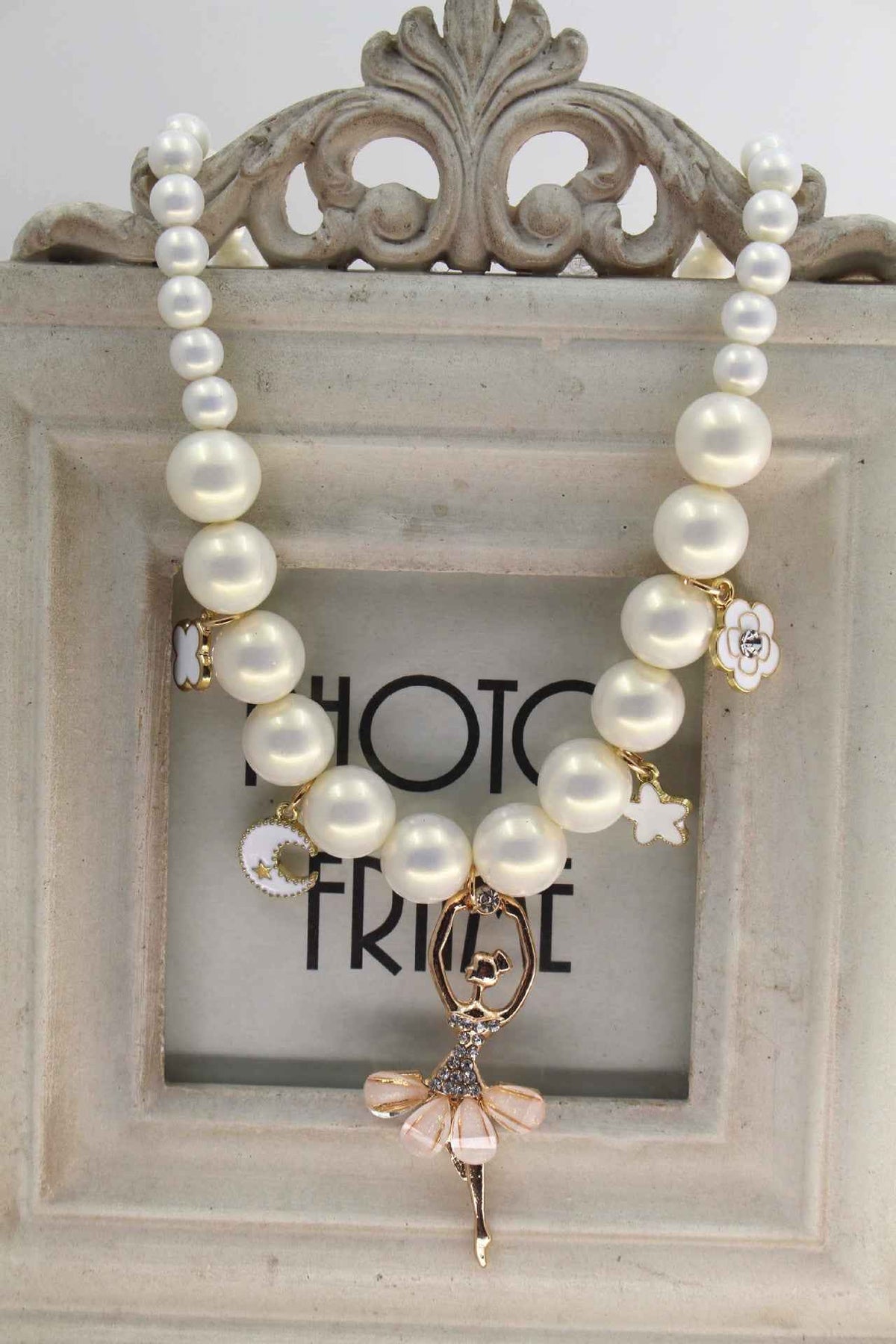White pearl necklace with gold-tone charms and a dangling bow pendant
