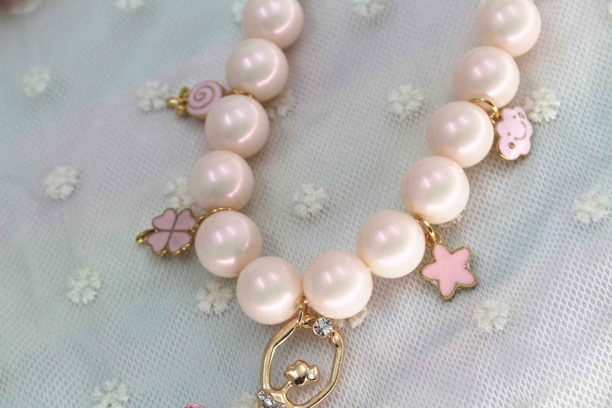 Pink pearl necklace with star and butterfly charms along a gold-tone clasp