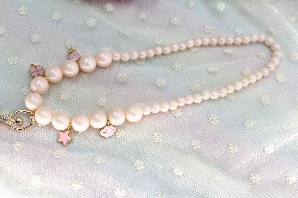 Pink and white pearl necklace with layered strands and dangling heart and flower charms
