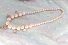 Pink and white pearl necklace with layered strands and dangling heart and flower charms