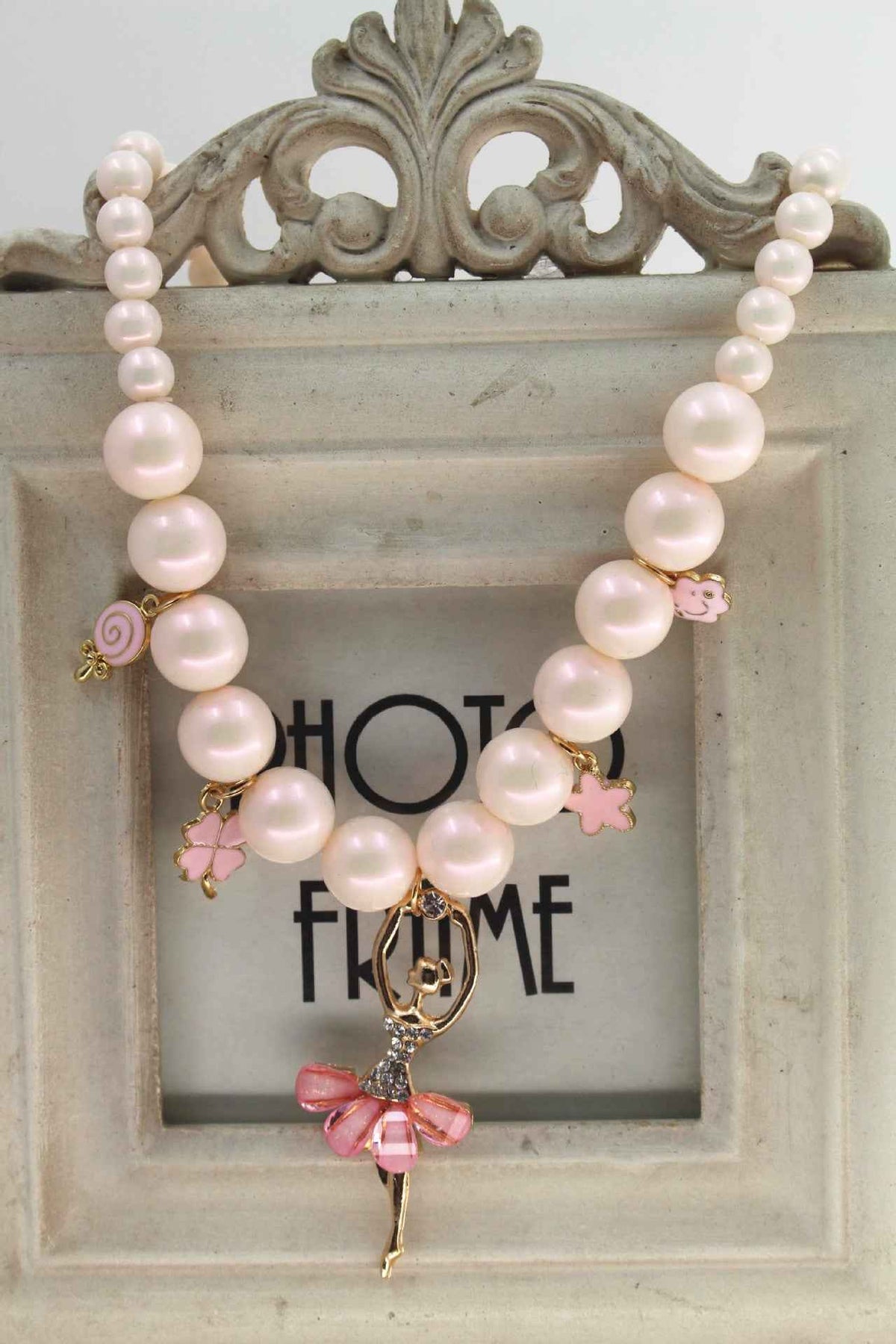 Pink pearl charm necklace with bow, star, and small flower accents