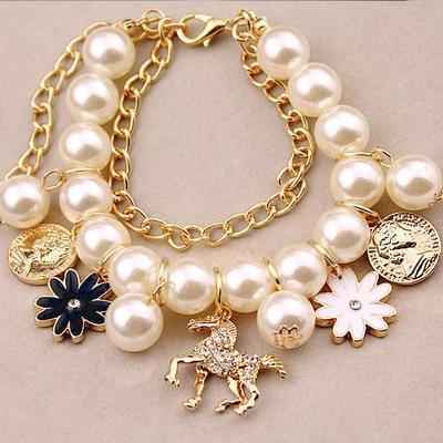Gold-tone pearl charm bracelet with blue flower, white flower, and horse coin dangles