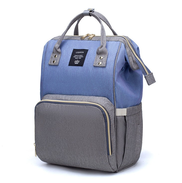 Maternity diaper bag in blue with gray front panel, top handles, and side bottle pockets
