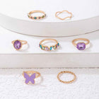 Gold ring set on display with purple gemstone, turquoise accents, and crystal band