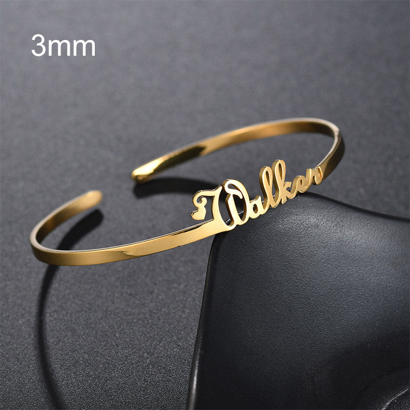 Gold personalized cuff bracelet with engraved cursive name, close-up view