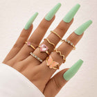 Gold boho stacking rings set with pink heart, zigzag, and butterfly charm details