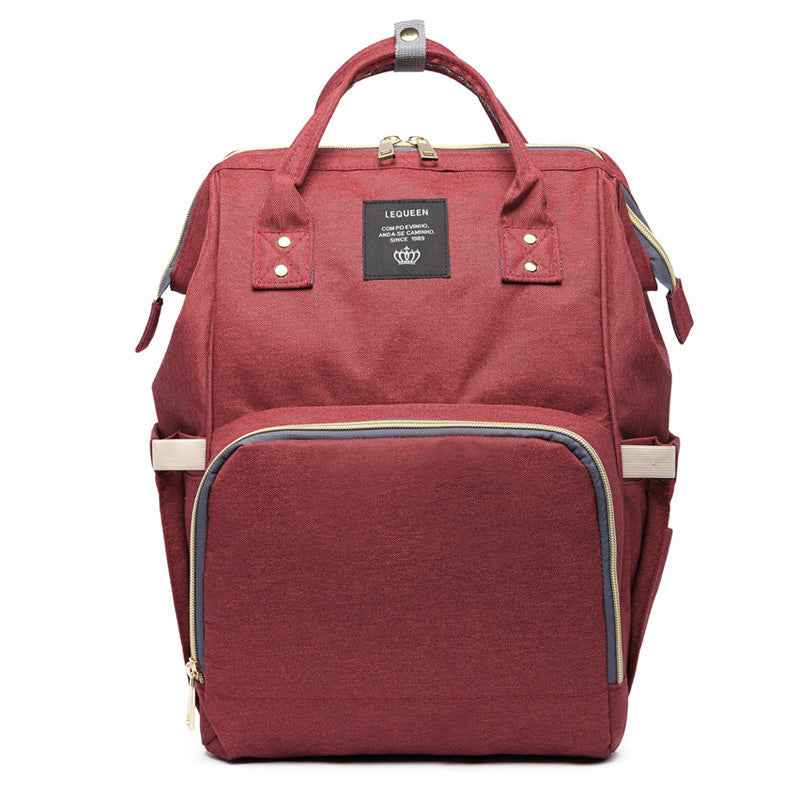 Burgundy maternity diaper bag with front zip pocket and teal trim, top handle and side straps