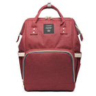 Burgundy maternity diaper bag with front zip pocket and teal trim, top handle and side straps