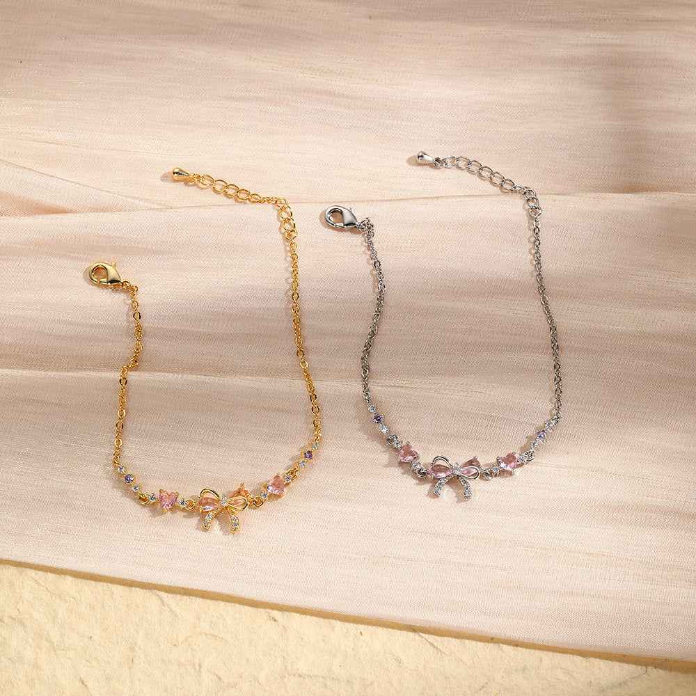 Two gold-tone rhinestone bracelet options with bow and pink heart accents