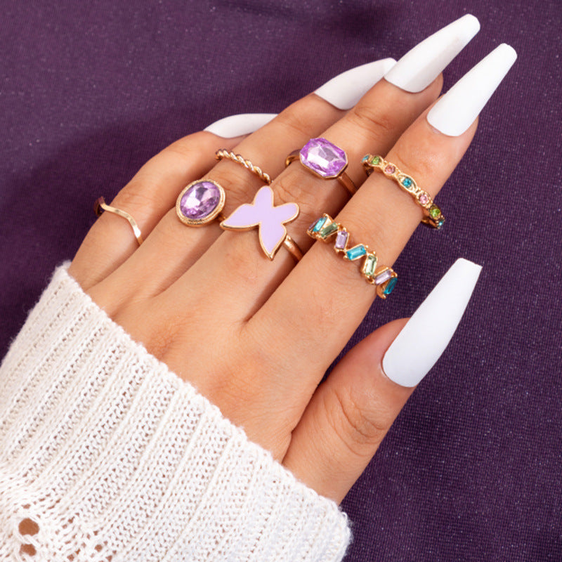 Gold boho stacking rings set with purple oval gemstone, cross charm, and turquoise stones