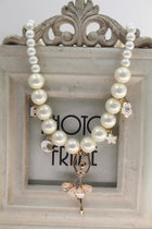 White pearl necklace with ballerina charm, star, and flower dangles on gold-tone chain