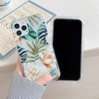 Tropical leaf iPhone case with green leaves and orange flowers, front shows blank screen