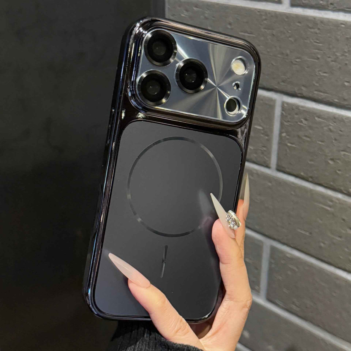 Dark phone case with silver-toned border and raised camera lens guard