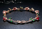 Rose gold crystal cuff with red, green, and clear gemstone settings