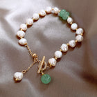 Freshwater pearl bracelet with white irregular pearls, green drop charms, and gold chain clasp