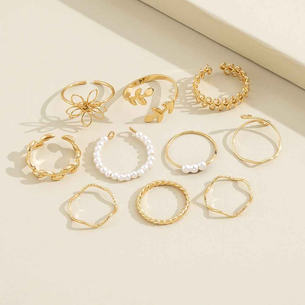 Gold-tone ring set laid out, including openwork flower and pearl bands