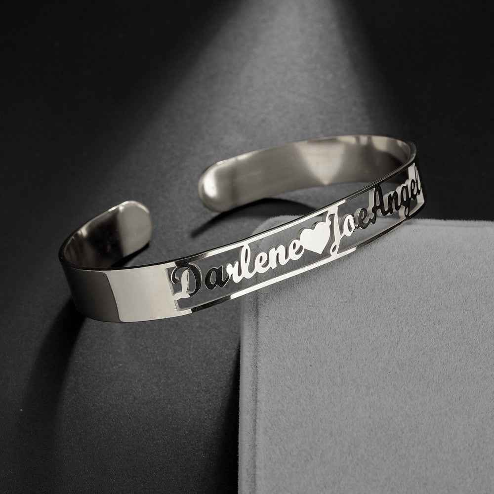 Silver stainless steel cuff bangle with engraved cursive name and open-heart cutout details