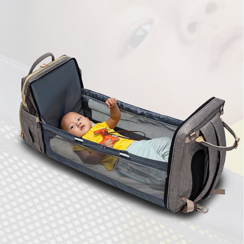 Foldable baby travel bed backpack, open dark blue with baby inside and mesh sides.