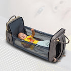 Foldable baby travel bed backpack, open dark blue with baby inside and mesh sides.
