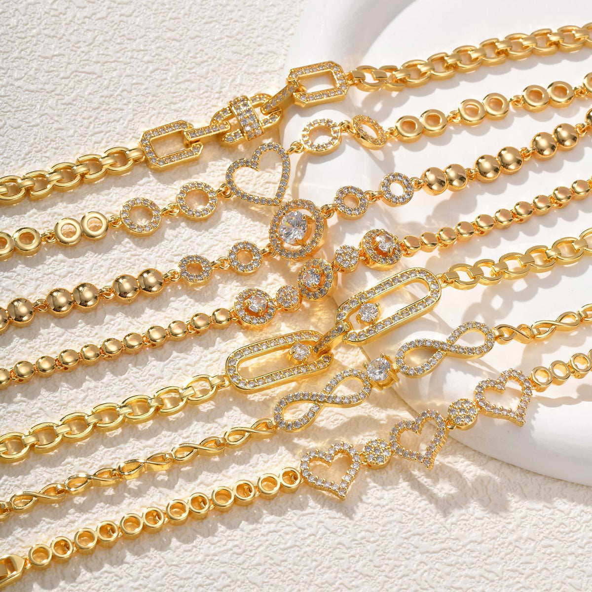 Gold-tone crystal link bracelet with heart and flower charms, close-up