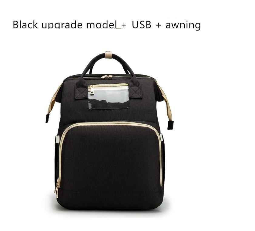 Black baby travel bed backpack with clear top pocket, beige trim, and gold hardware