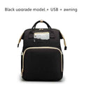 Black baby travel bed backpack with clear top pocket, beige trim, and gold hardware